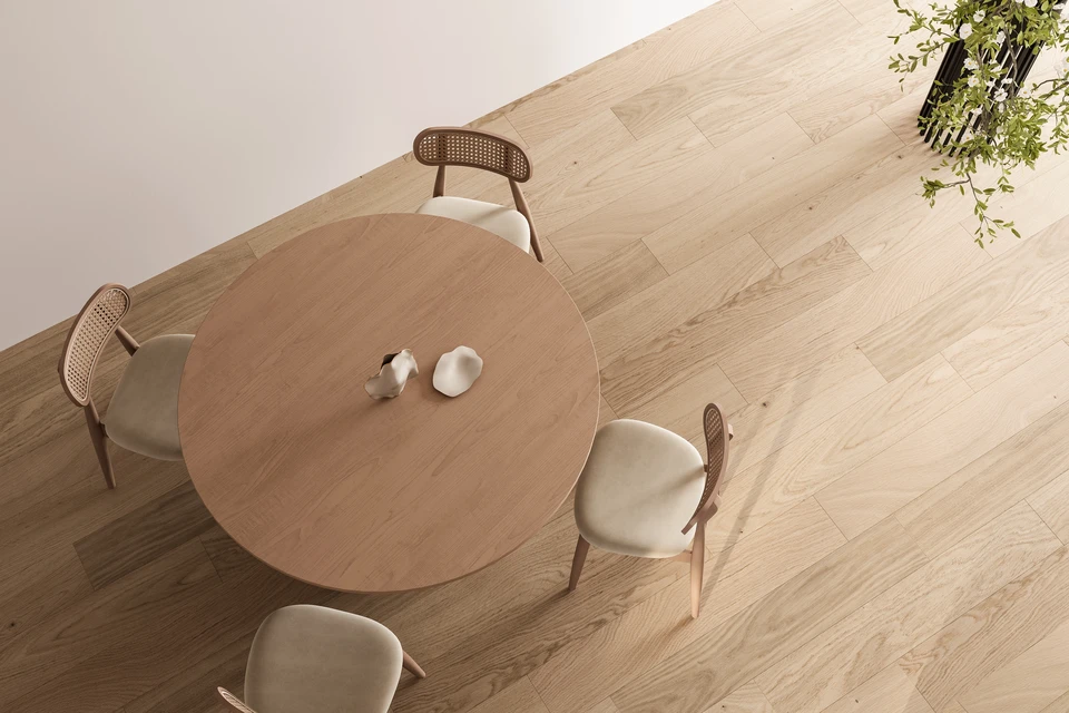 Photographie d'un intérieur résidentiel moderne et chaleureux présentant un parquet fraîchement posé de haute qualité. La scène montre un salon ou une pièce à vivre avec un parquet en bois naturel (essences claires ou chêne) parfaitement aligné et fini, mettant en évidence l'uniformité et la rigueur de la pose. La lumière naturelle illumine le sol, révélant la chaleur et l'éclat du bois. La composition inclut quelques meubles ou éléments d'ambiance (meuble bas, plante, coin d'un escalier ou d'une porte) pour contextualiser le parquet dans un intérieur réel et valorisé. L'image doit transmettre solidité, élégance et professionnalisme du travail artisanal.